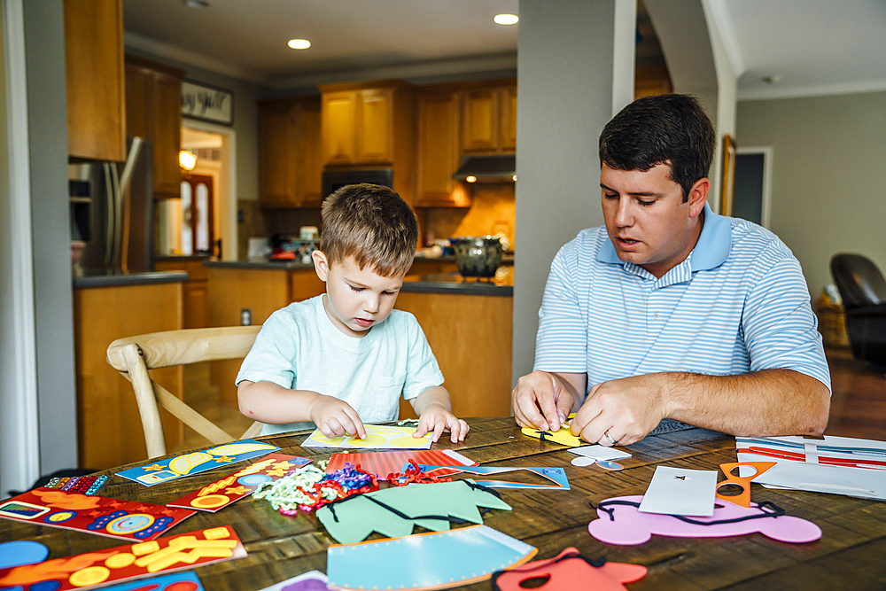 Caucasian father and son making masks at table