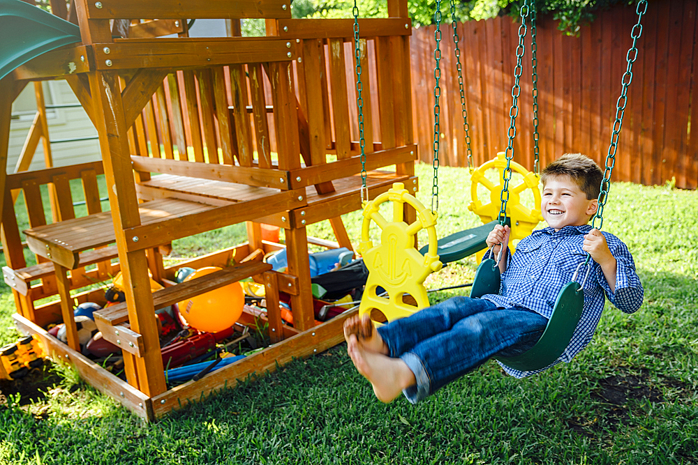 Smiling Caucasian boy n swing in backyard