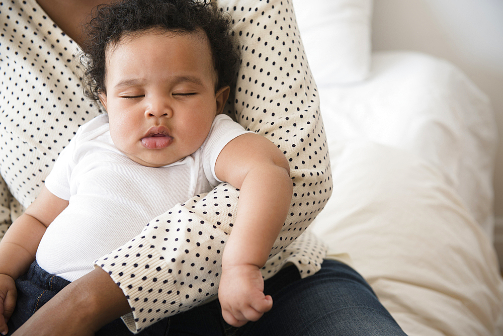 Mother holding sleeping baby son in lap