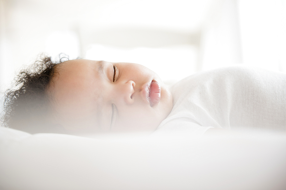 Mixed Race baby boy sleeping on bed