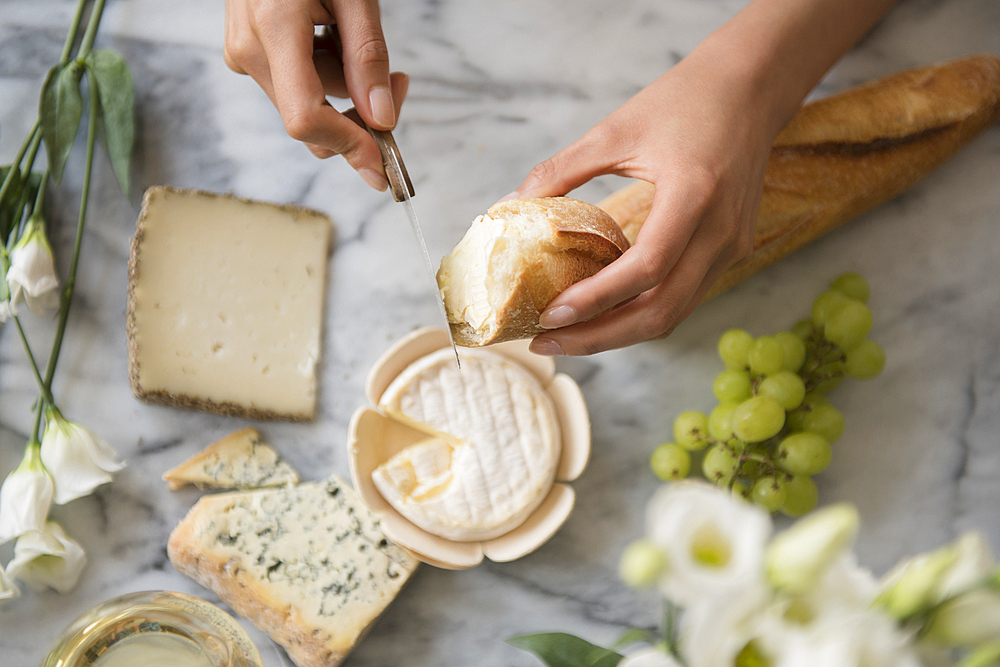 Hispanic woman spreading cheese on bread