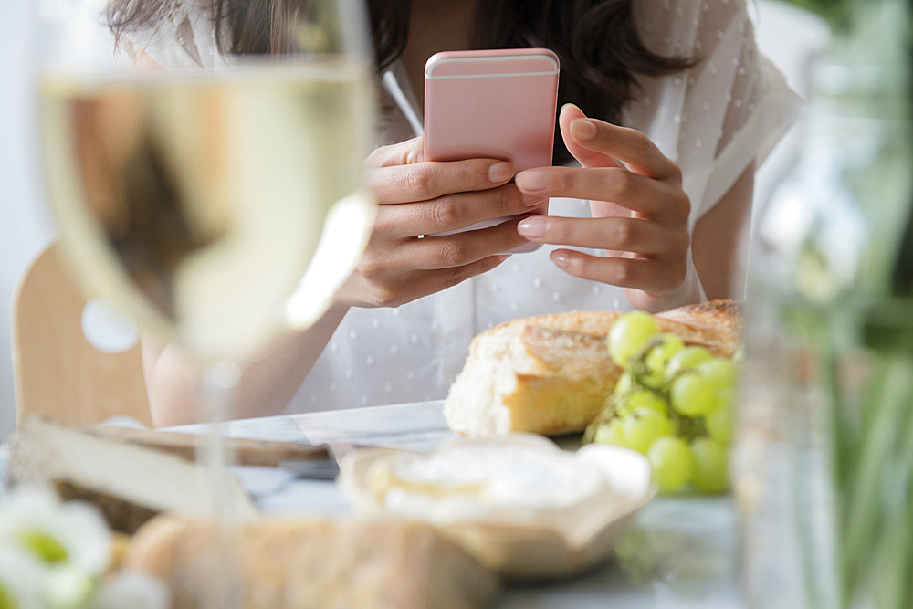 Hispanic woman texting on cell phone at table