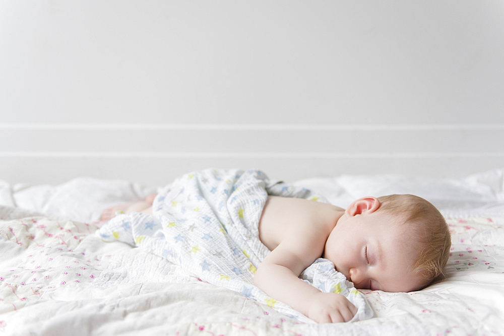 Caucasian baby boy sleeping on bed