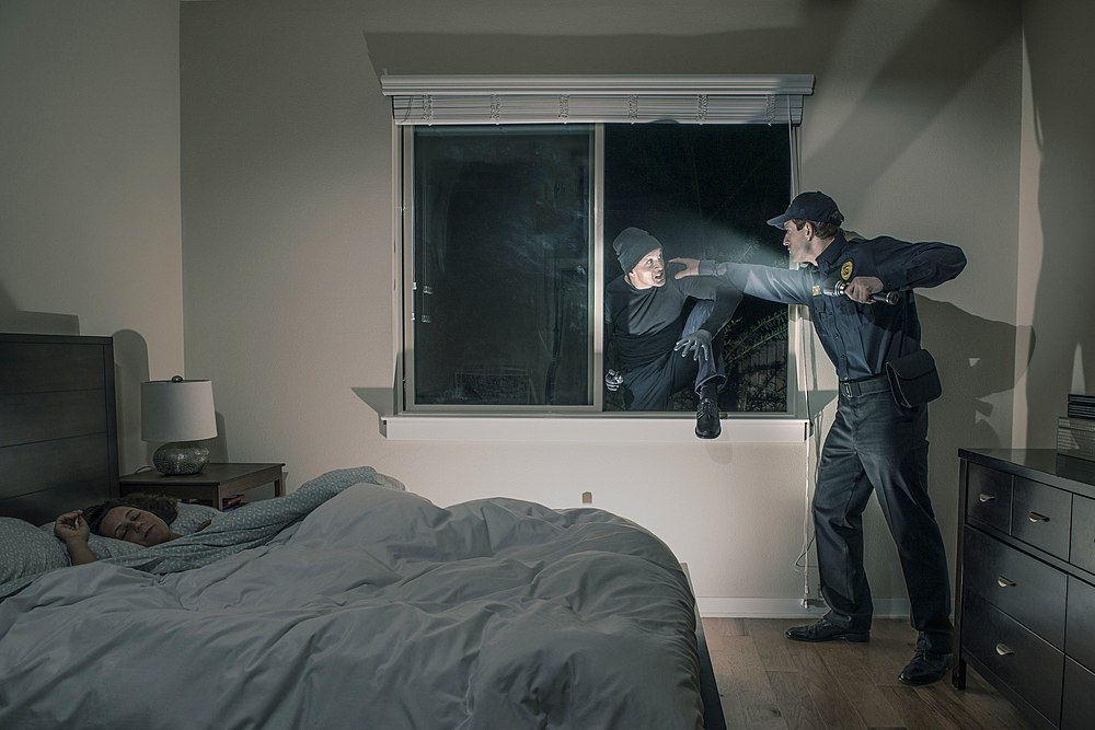 Caucasian police officer shining flashlight on house burglar