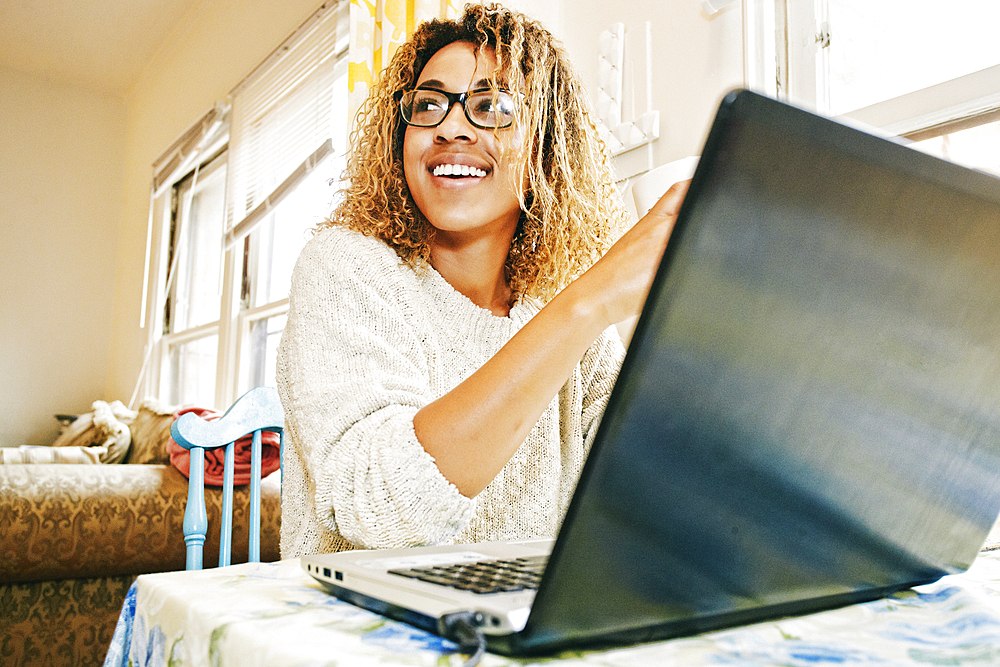 Smiling Mixed Race woman using laptop