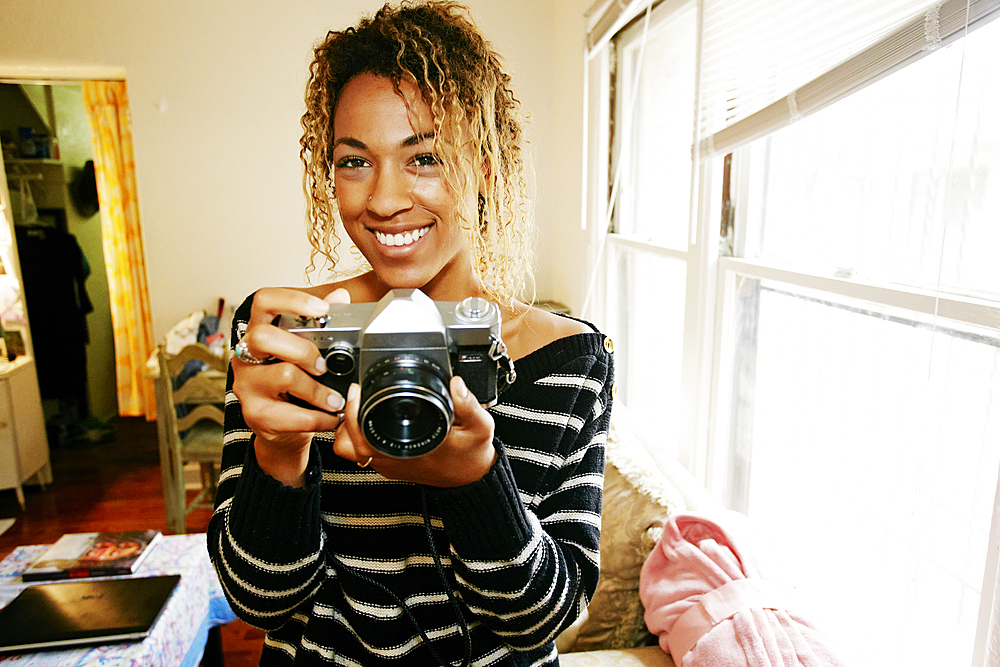 Smiling Mixed Race woman focusing camera lens