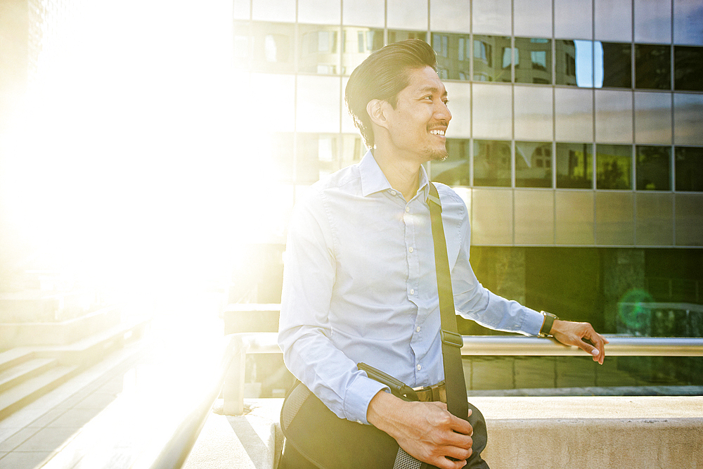 Smiling Mixed Race businessman walking outdoors on sunny day