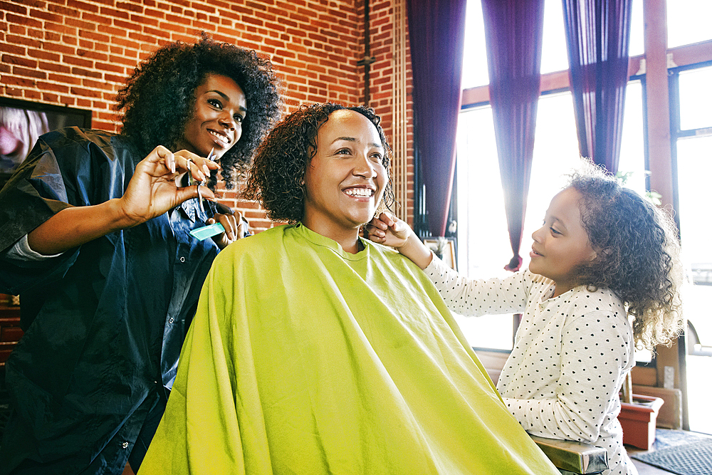 Smiling hairdresser and customers in hair salon