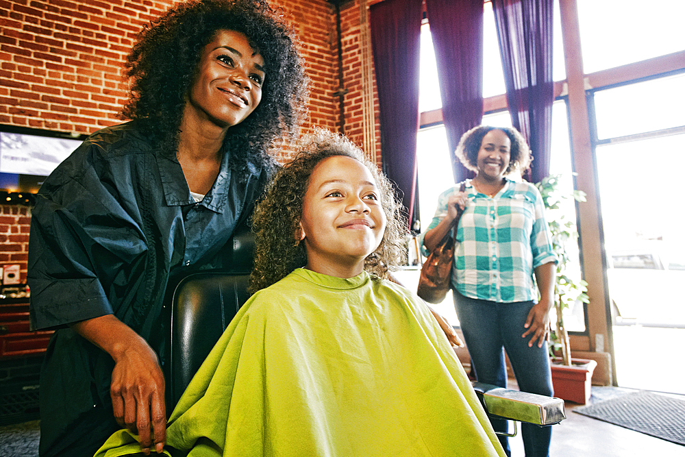 Smiling hairdresser and customers in hair salon