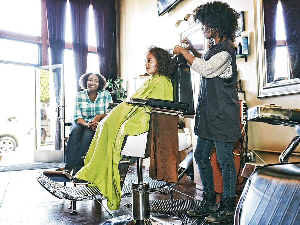 Smiling hairdresser and customers in hair salon