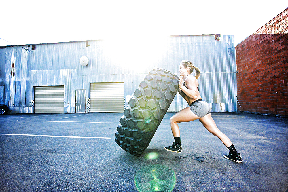 Caucasian woman working out with heavy tire outdoors