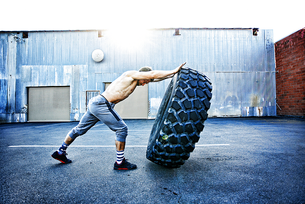 Caucasian man working out with heavy tire outdoors