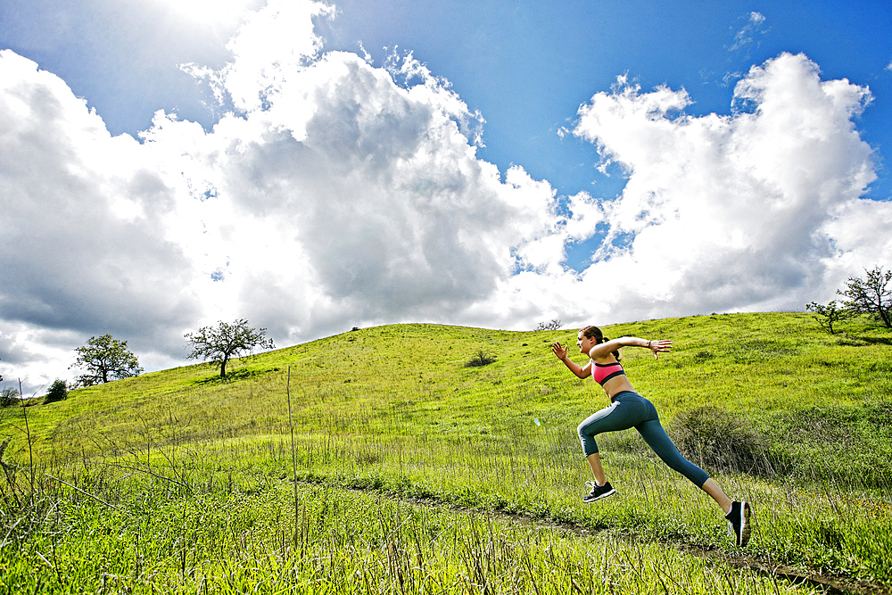 Caucasian woman running on hill