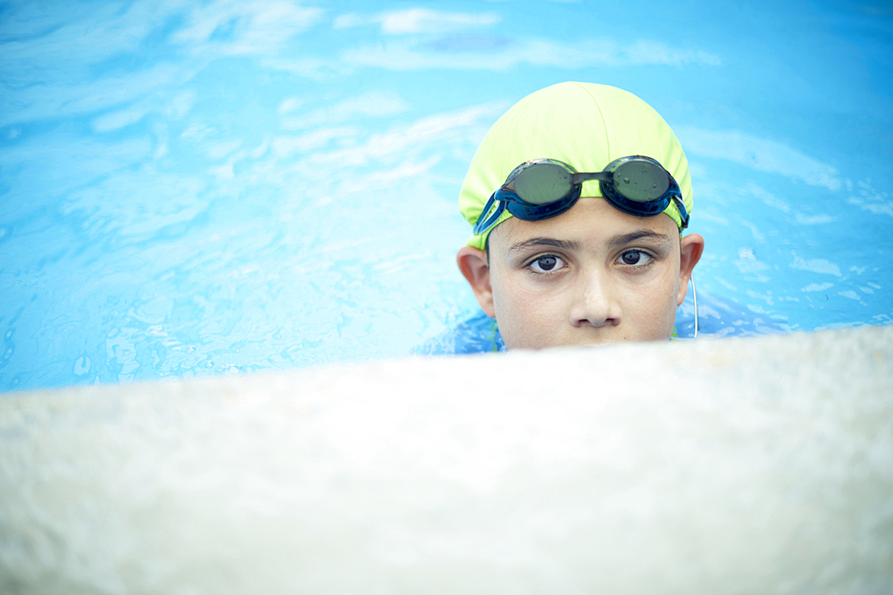 Hispanic boy swimming with swimming cap and goggles