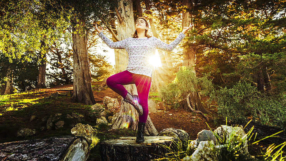 Mixed Race girl meditating on tree stump