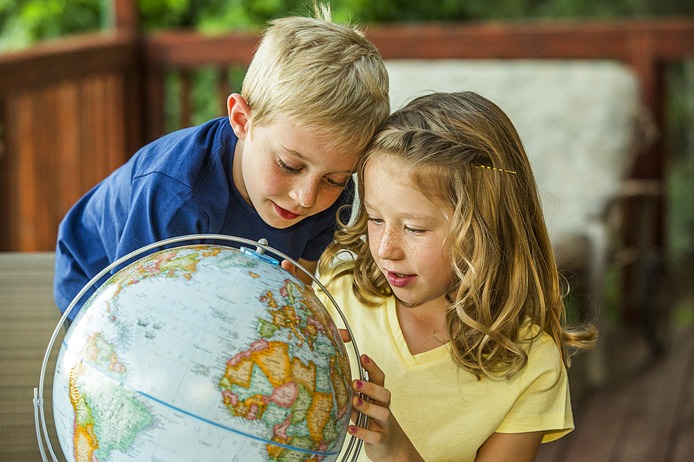 Caucasian brother and sister examining globe