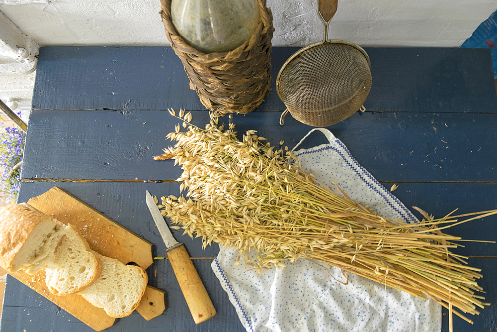 Wheat, sliced bread, sieve and bottle on bench