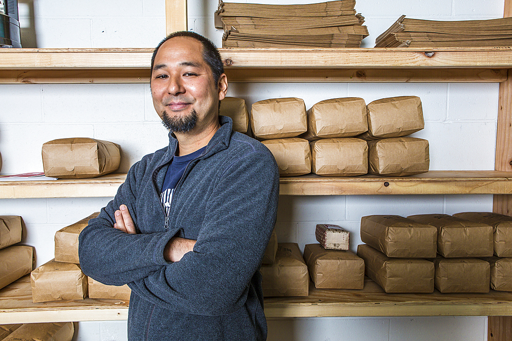 Mixed Race man posing near shelves of coffee bags