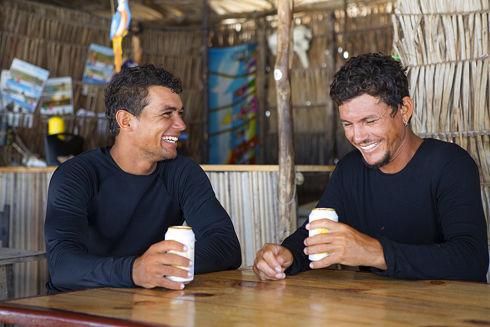 Laughing men holding beverage cans in bar