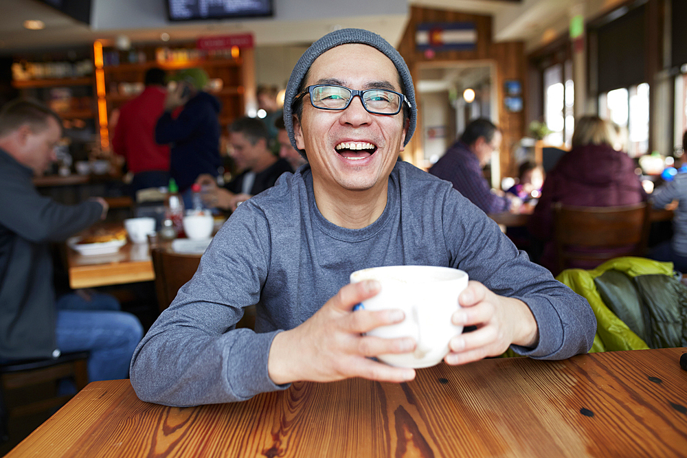 Laughing Asian man in coffee shop