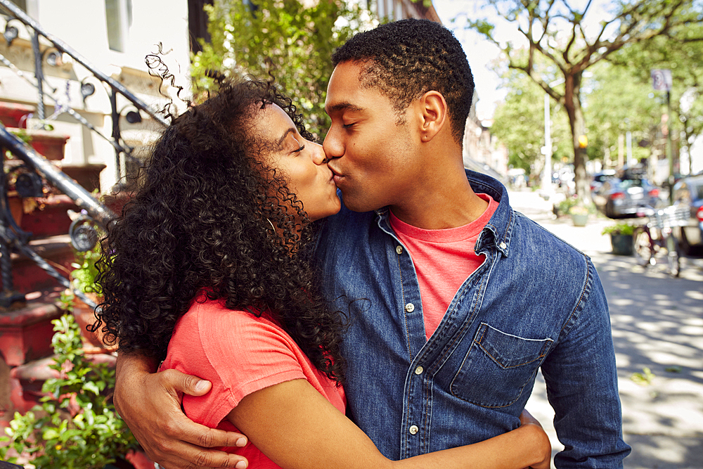 Smiling couple kissing on city sidewalk