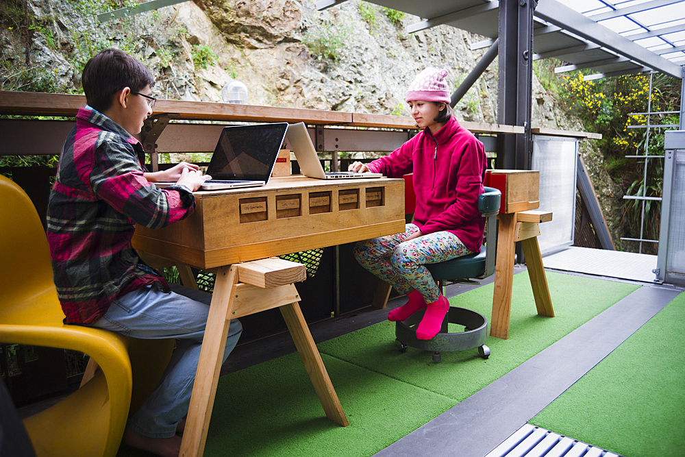 Mixed Race brother and sister using laptops on veranda