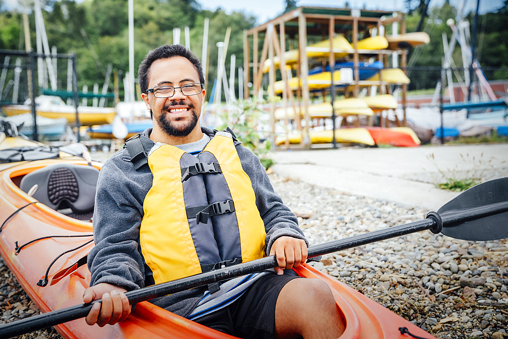 Mixed Rave man sitting in kayak holding paddle