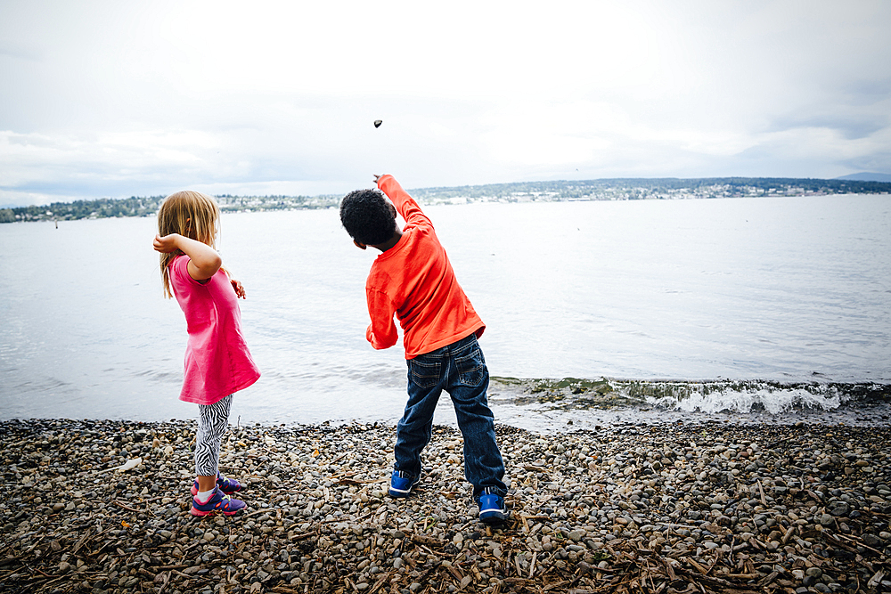 Boy and girl throwing rocks into river