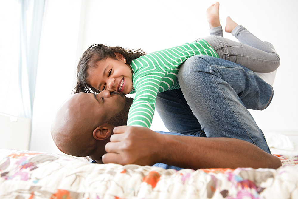 Father kissing daughter on bed