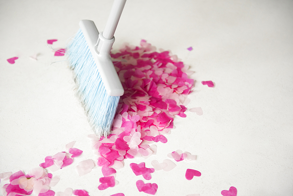 Broom sweeping heart-shape confetti on floor