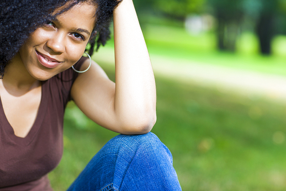 Smiling Mixed Race woman sitting in park