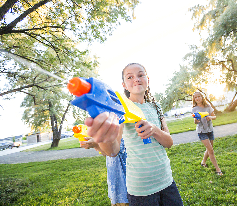 Caucasian girls playing with squirt guns