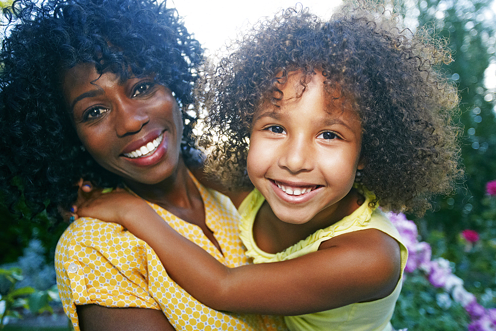 Smiling mother and daughter posing outdoors