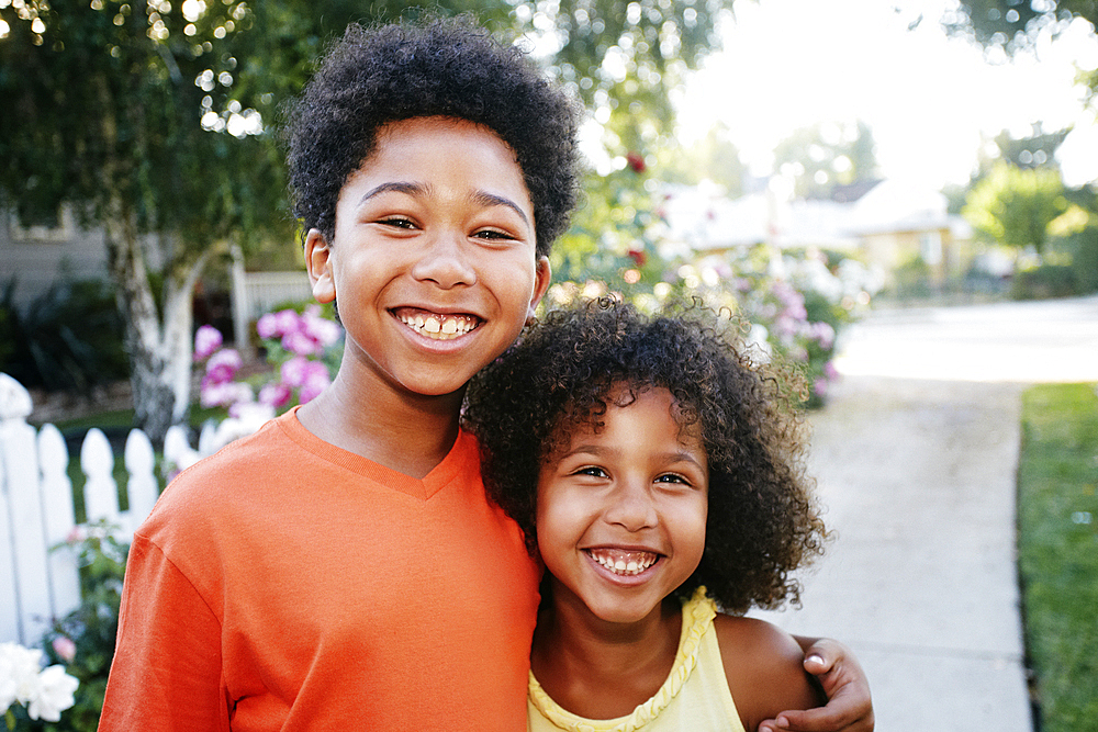 Smiling Mixed Race brother and sister hugging outdoors