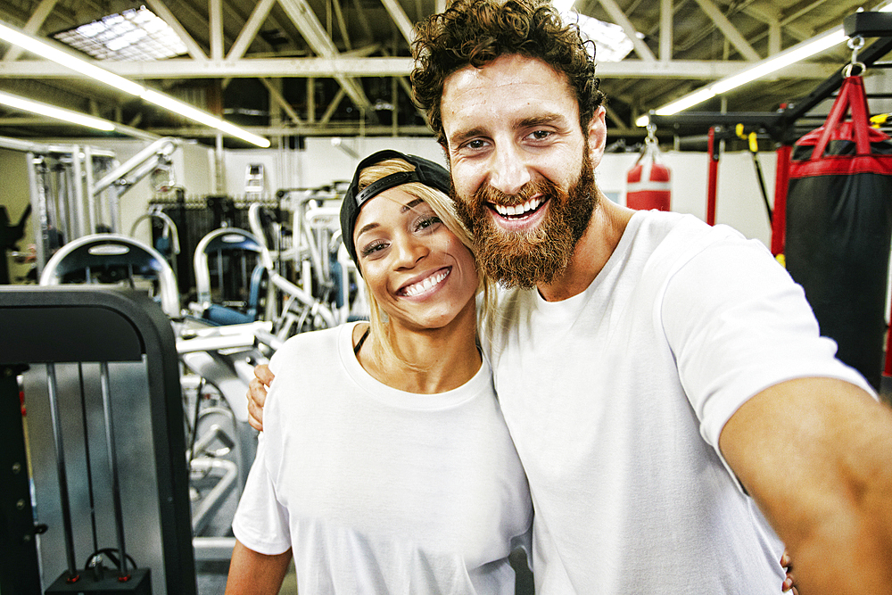 Mixed Race man couple posing for cell phone selfie in gymnasium