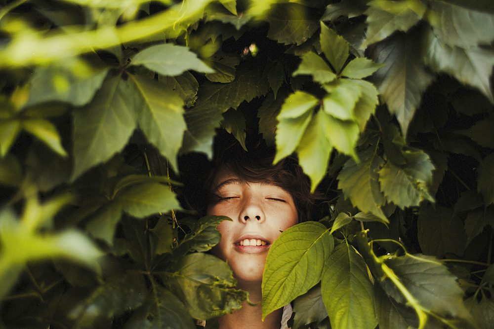 Caucasian boy smiling in leaves