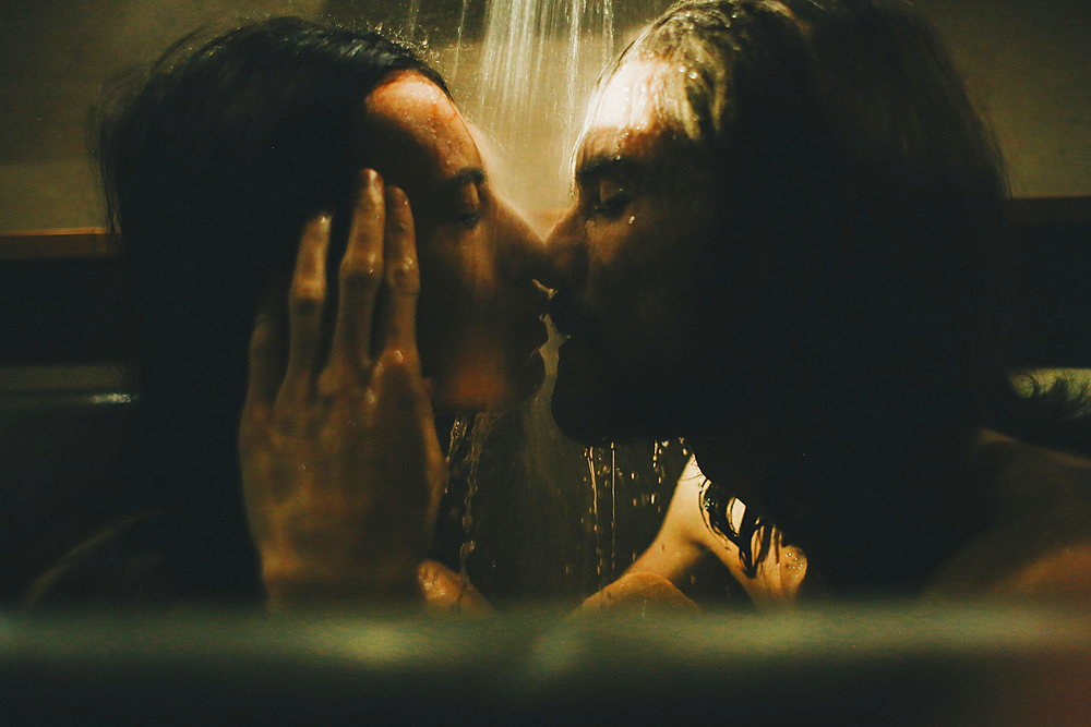 Caucasian couple relaxing in bathtub under shower