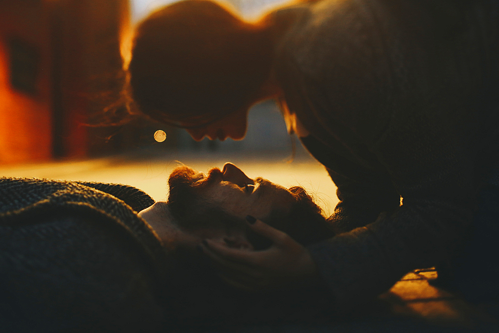 Caucasian woman caressing man laying on floor