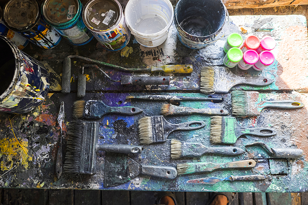 Used paintbrushes and paint cans on table