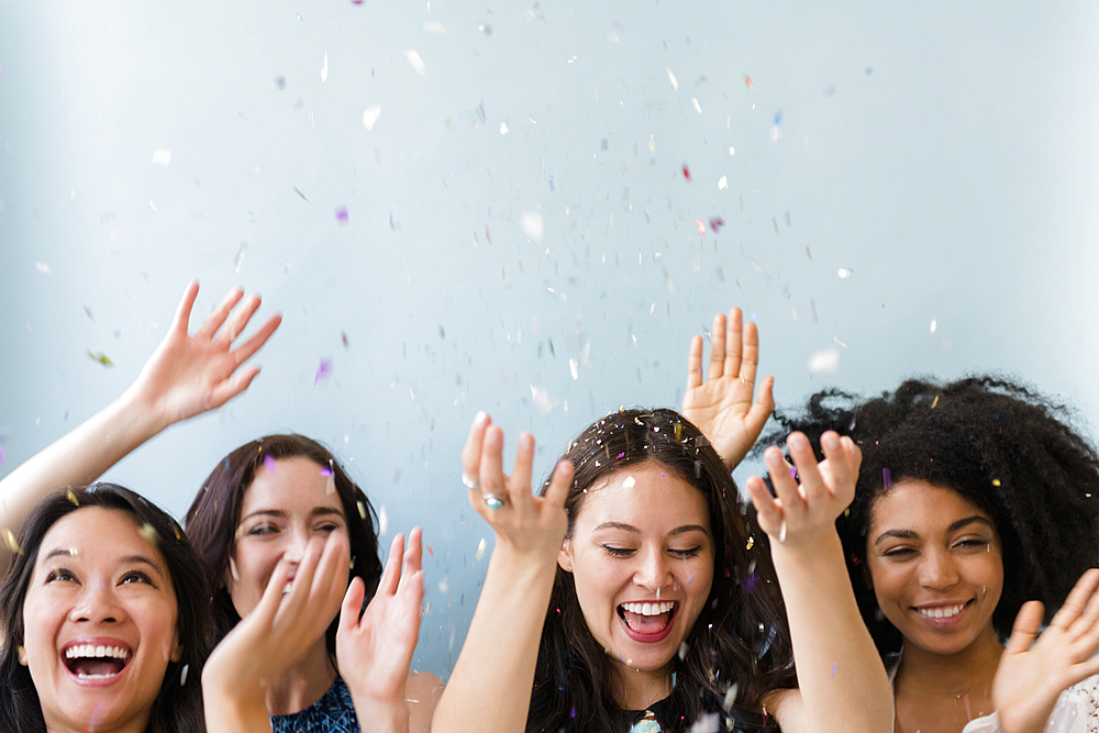 Smiling women throwing confetti