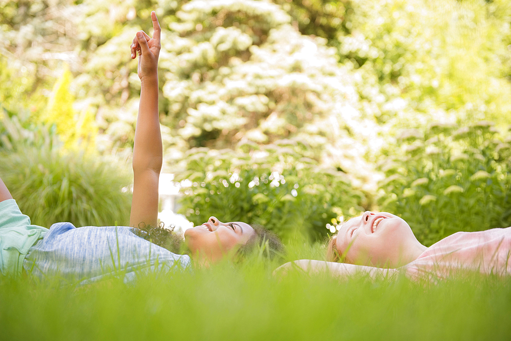 Smiling girls laying in grass pointing up