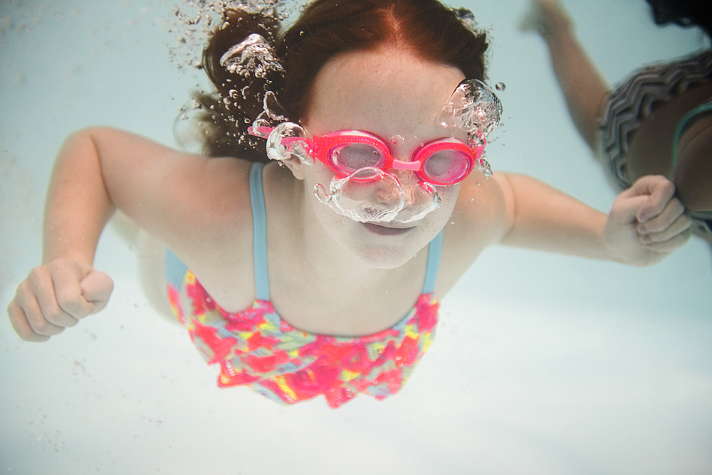 Girl swimming underwater wearing goggles