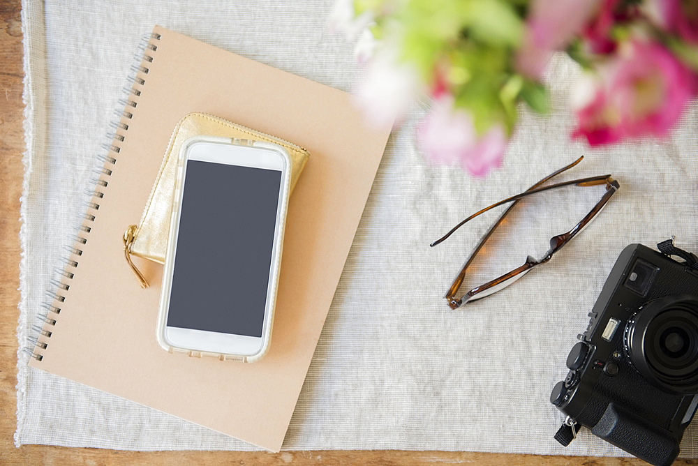 Camera, cell phone, purse, notebook and wallet on table