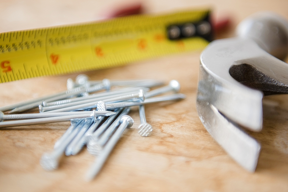 Hammer, nails and tape measure on table