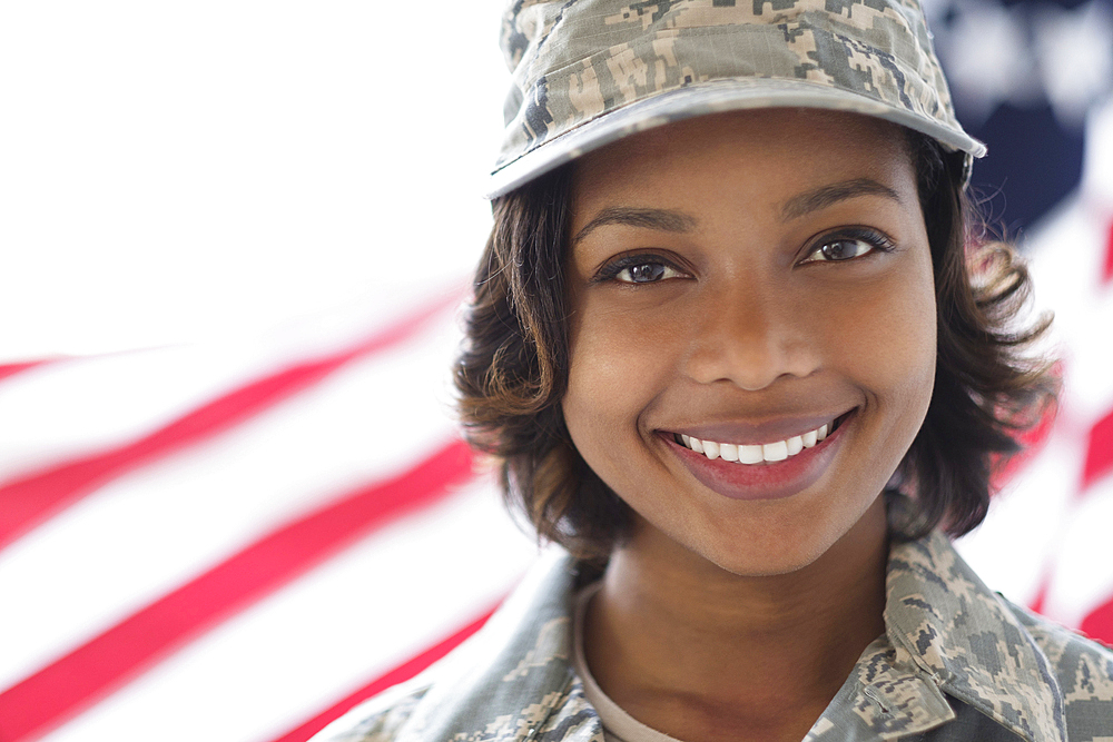 Portrait of smiling Mixed Race soldier near American flag