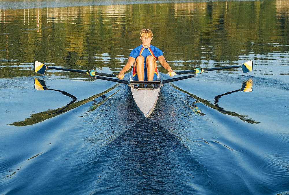 Caucasian man rowing on river