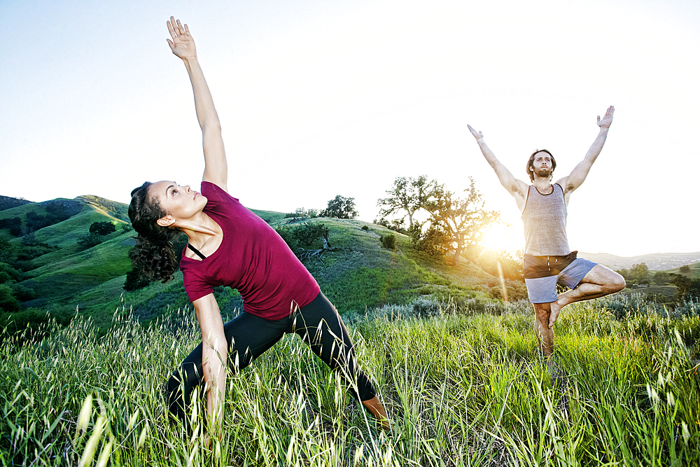 Couple practicing yoga on hill