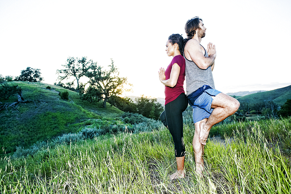 Couple practicing yoga on hill