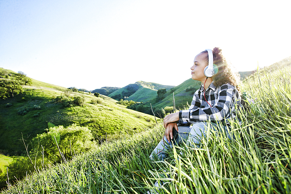 Girl sitting on hill listening to headphones