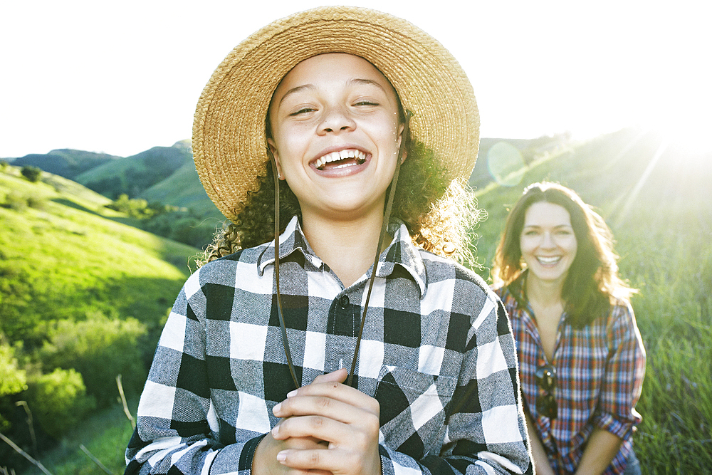 Portrait of mother and daughter laughing on hill